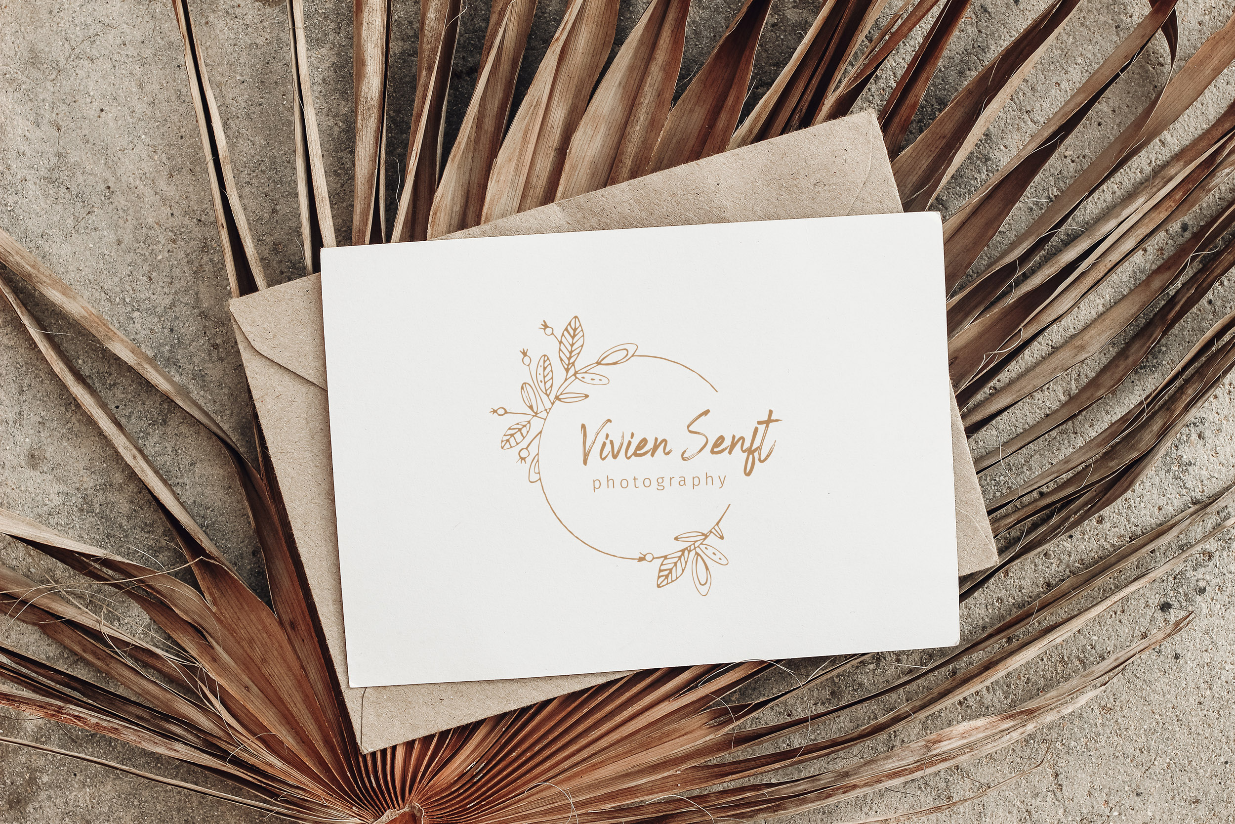 Summer stationery still life. Closeup of blank card mock-up and craft envelope on dry palm leaf. Grunge beige concrete background. Flat lay, top view. Tropical vacation concept. Moody boho design